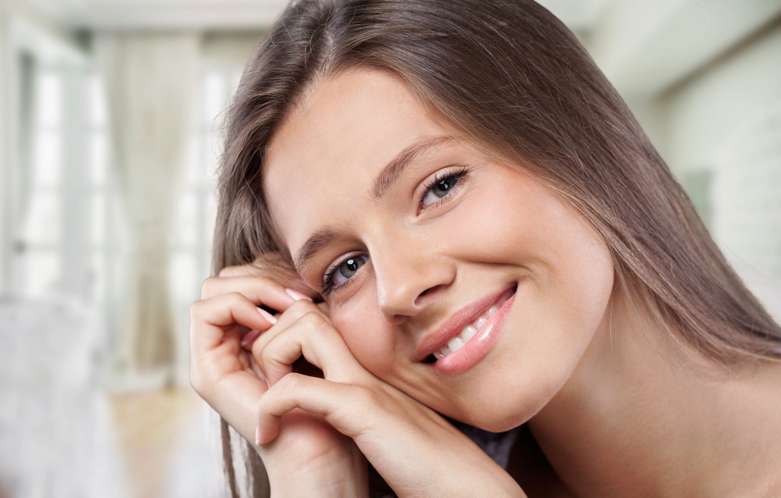 Close-up of a woman smiling with her hand on her face after Lumineers treatment