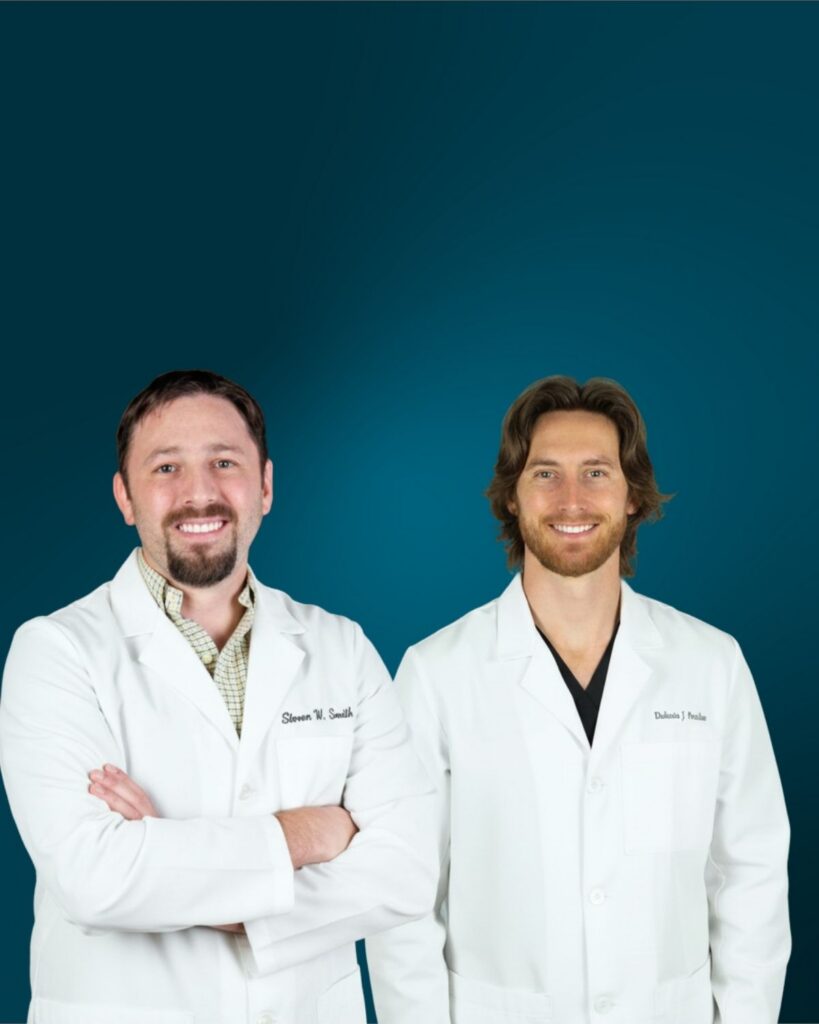 Dr. Steven W. Smith and Dr. Dakota James Peachee, dentists at Myrtle Grove Implant & Family Dentistry in Wilmington, NC, wearing white lab coats