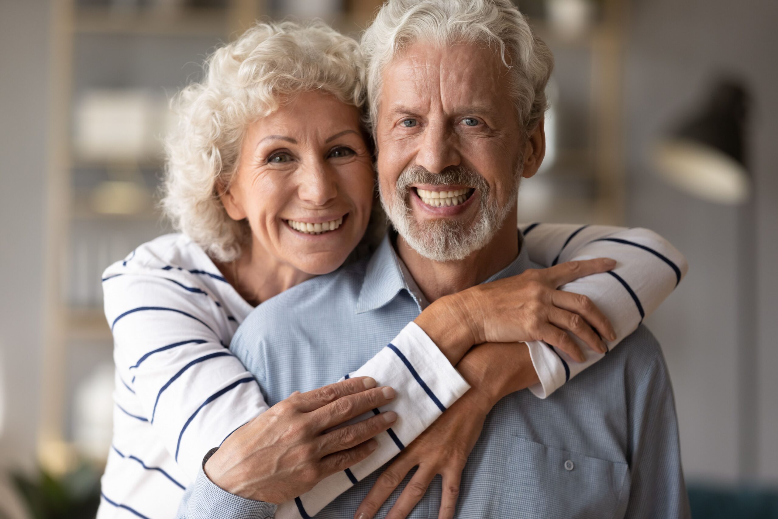 Elderly couple embracing and smiling after dental implant treatment at Myrtle Grove Implant & Family Dentistry