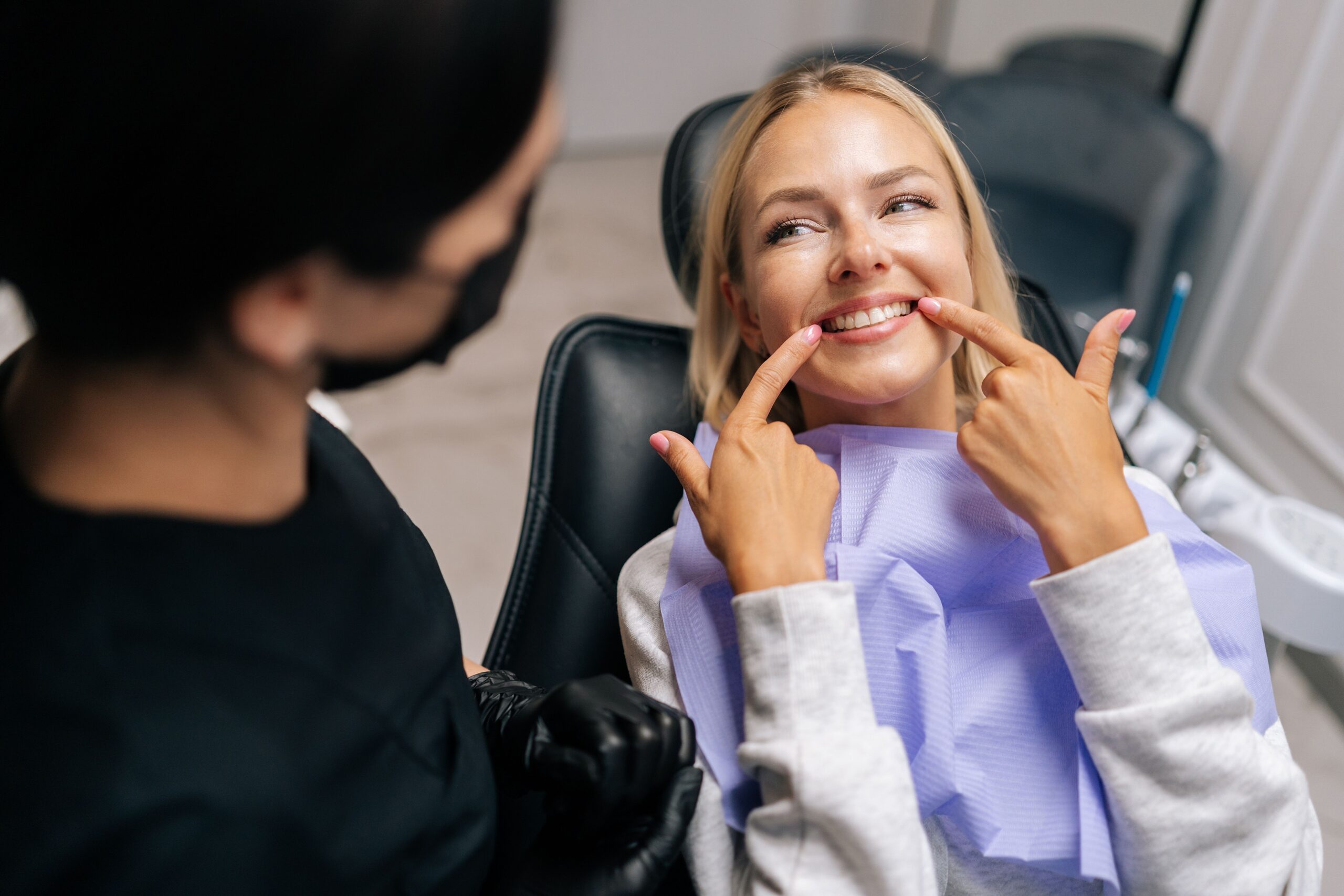 Patient sitting in a dental chair pointing at her teeth at Myrtle Grove Implant & Family Dentistry