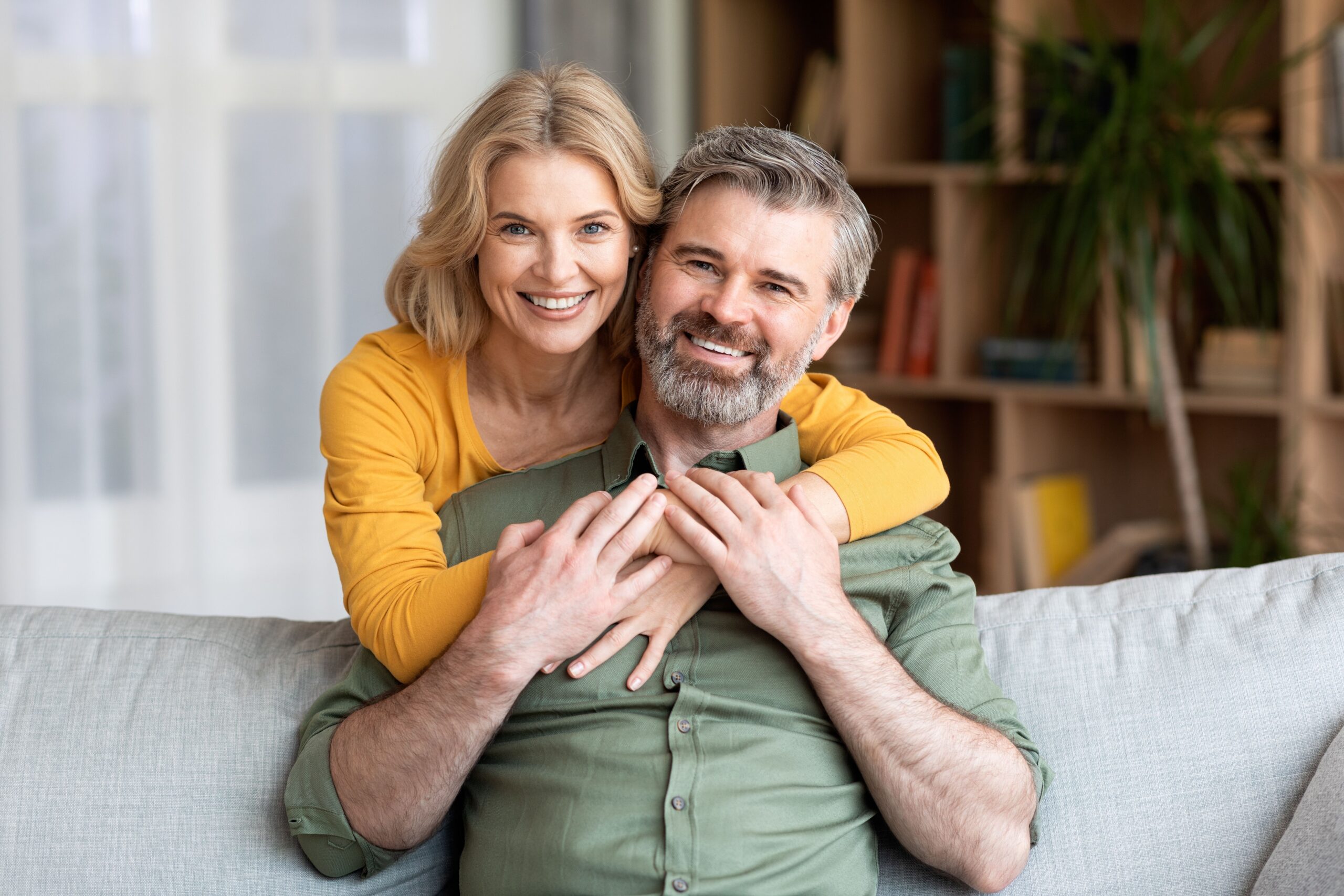 Woman hugging her partner on a couch after root canal treatment at Myrtle Grove Implant & Family Dentistry